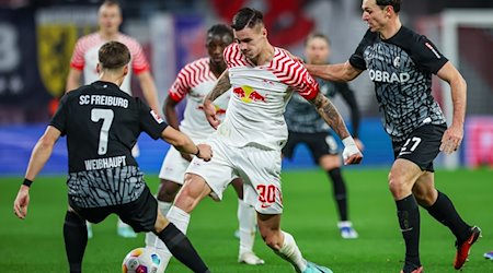 Leipzigs Spieler Benjamin Sesko (M) versucht, sich gegen Freiburgs Noah Weisshaupt (l) und Nicolas Höfler durchzusetzen. / Foto: Jan Woitas/dpa/Archivbild