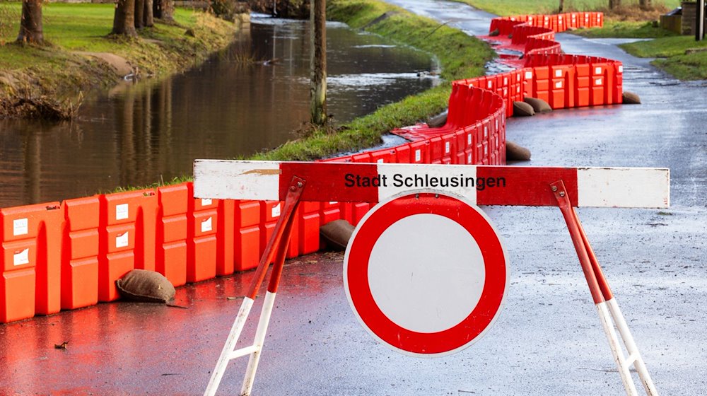 Eine Absperrung steht neben einem mobilen Damms, der Anwohner des Ortsteils Rappelsdorf vor dem Fluß Schleuse schützen soll. / Foto: Michael Reichel/dpa