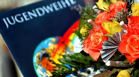Eine Jugendweihe-Urkunde liegt in der Stadthalle in Burg neben einem Blumenstrauß. / Foto: Andreas Lander/dpa-Zentralbild/dpa