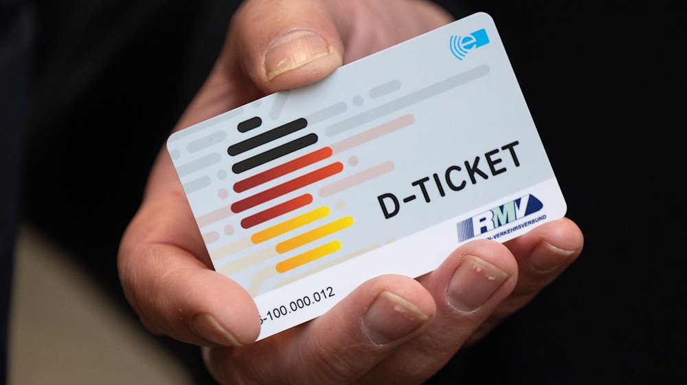 Eine Hand hält ein Deutschlandticket. / Foto: Boris Roessler/dpa