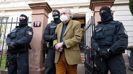 Bei einer Razzia gegen «Reichsbürger» führen vermummte Polizisten nach der Durchsuchung eines Hauses Heinrich XIII. Prinz Reuß (2.v.r.) zu einem Polizeifahrzeug. / Foto: Boris Roessler/dpa