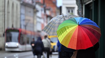 Fußgänger laufen mit Regenschirmen durch die Marktstraße. / Foto: Martin Schutt/dpa