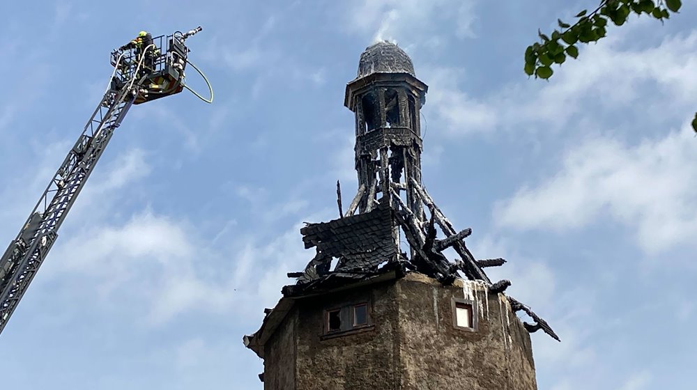 Feuerwehrkräfte sind an der Spitze vom historischen Neutorturm in Arnstadt auf einer Leiter zu sehen. / Foto: Christopher Kissmann/dpa
