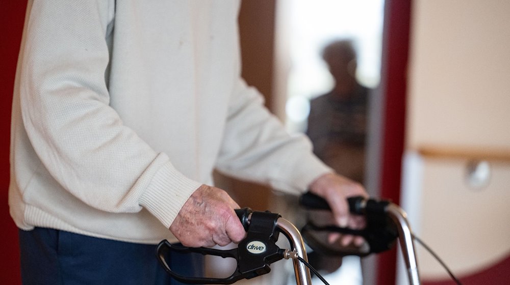 Ein Bewohner eines Pflegeheims geht mit einem Rollator einen Gang entlang. / Foto: Marijan Murat/dpa