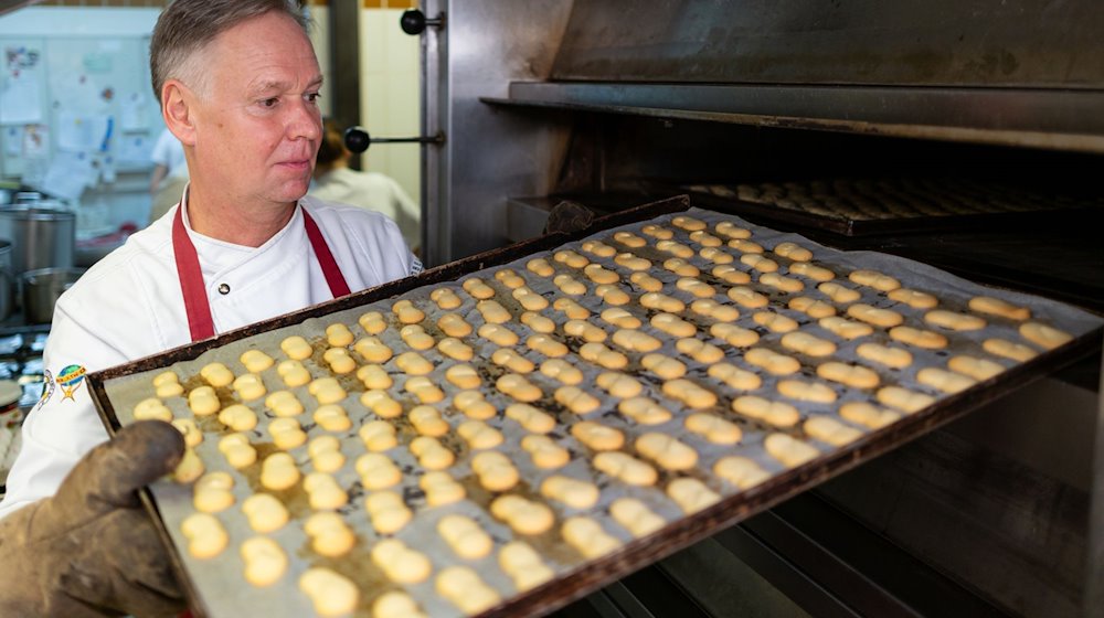 Stefan Lobenstein, Konditormeister und Präsident der Handwerkskammer Erfurt, holt in der Bäckerei und Konditorei Lobenstein ein Blech voller Plätzchen aus dem Backofen. Trotz vieler Probleme hat ein Großteil der Handwerker in Thüringen den Optimismus nicht verloren. / Foto: Michael Reichel/dpa