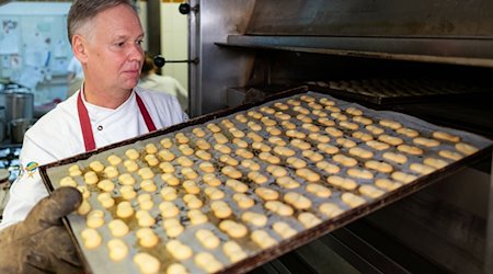 Stefan Lobenstein, Konditormeister und Präsident der Handwerkskammer Erfurt, holt in der Bäckerei und Konditorei Lobenstein ein Blech voller Plätzchen aus dem Backofen. Trotz vieler Probleme hat ein Großteil der Handwerker in Thüringen den Optimismus nicht verloren. / Foto: Michael Reichel/dpa