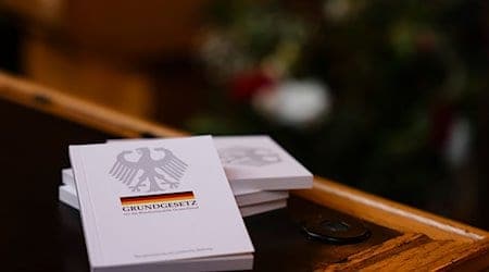 Vier Bücher mit dem Grundgesetz liegen auf einem Tisch im Ratssaal des Kieler Rathauses. / Foto: Frank Molter/dpa