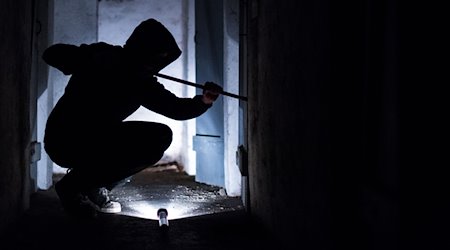 Ein Mann hebelt mit einem Brecheisen eine Tür im Keller eines Wohnhauses auf. / Foto: Silas Stein/dpa