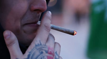 Ein Teilnehmer einer kleinen Mahnwache zur Cannabis-Liberalisierung raucht einen Cannabis-Joint. / Foto: Bodo Schackow/dpa/Symbolbild