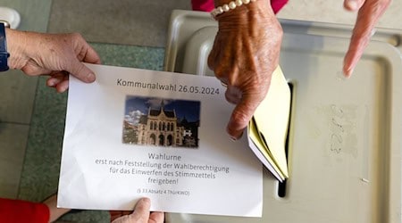 Eine Frau steckt bei den Kommunalwahlen in Thüringen in einem Wahllokal ihre Wahlzettel in die Wahlurne. / Foto: Michael Reichel/dpa