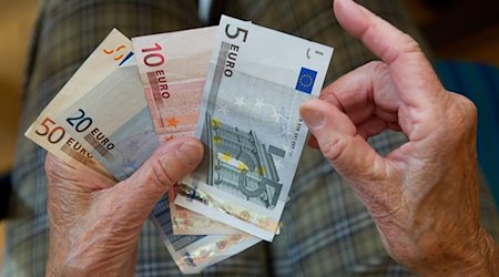 Eine ältere Frau zählt Geld. / Foto: Marijan Murat/dpa/Symbolbild
