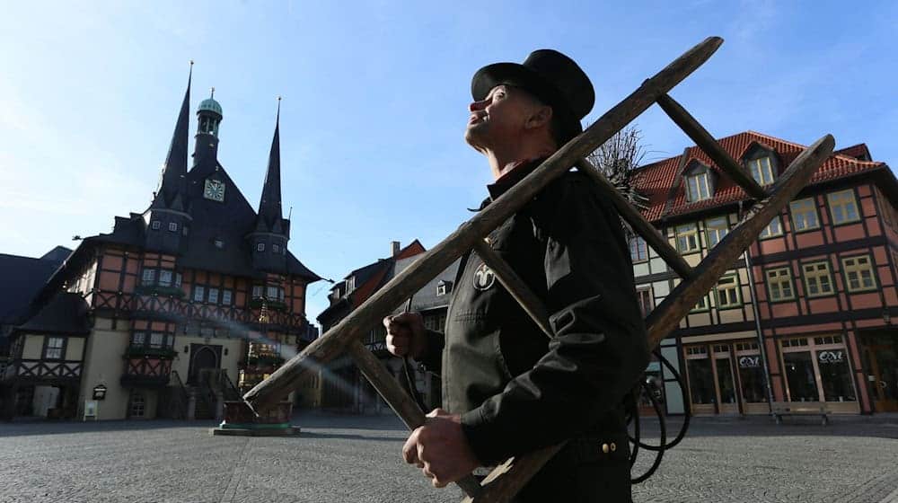 Ein Schornsteinfeger steht auf dem Marktplatz in Wernigerode vor einem Wohnhaus. / Foto: Matthias Bein/dpa-Zentralbild/dpa/Archivbild