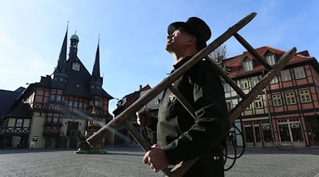 Ein Schornsteinfeger steht auf dem Marktplatz in Wernigerode vor einem Wohnhaus. / Foto: Matthias Bein/dpa-Zentralbild/dpa/Archivbild