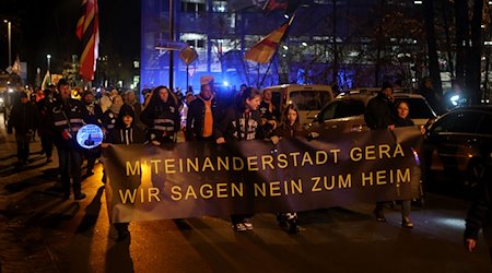Teilnehmer einer Demonstration gegen eine geplante Erstaufnahmeeinrichtung für Flüchtlinge im ehemaligen Wismut Krankenhaus laufen zu dem Krankenhausgelände. / Foto: Bodo Schackow/dpa