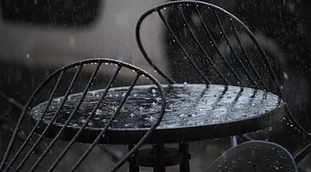 Hagel und Regen prasseln auf einen Tisch vor einem Café. / Foto: Britta Pedersen/dpa