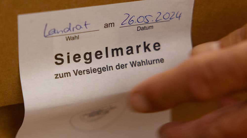 Ein Wahlhelfer entfernt in der Bibliothek im Alten Rathaus Hildburghausen die Siegelmarke einer Wahlurne. / Foto: Michael Reichel/dpa