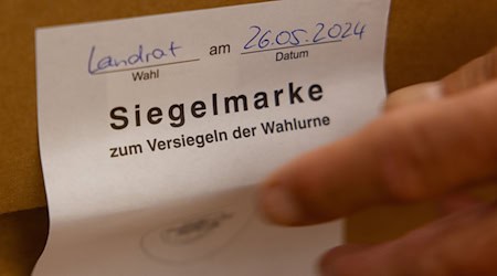 Ein Wahlhelfer entfernt in der Bibliothek im Alten Rathaus Hildburghausen die Siegelmarke einer Wahlurne. / Foto: Michael Reichel/dpa