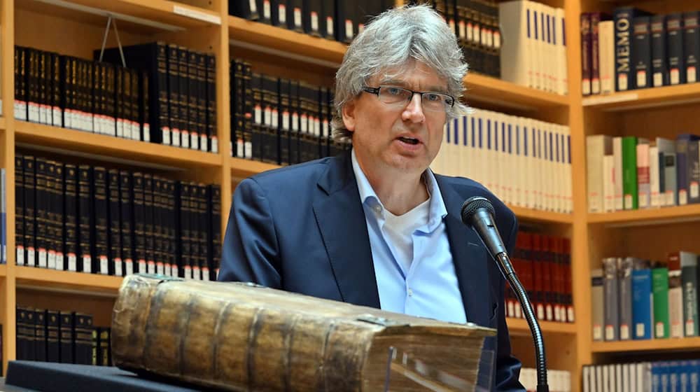 Reinhard Laube, Direktor der Herzogin Anna Amalia Bibliothek, spricht über eine restaurierte 270 Jahre alte Bibel aus dem Ahrtal. / Foto: Martin Schutt/dpa