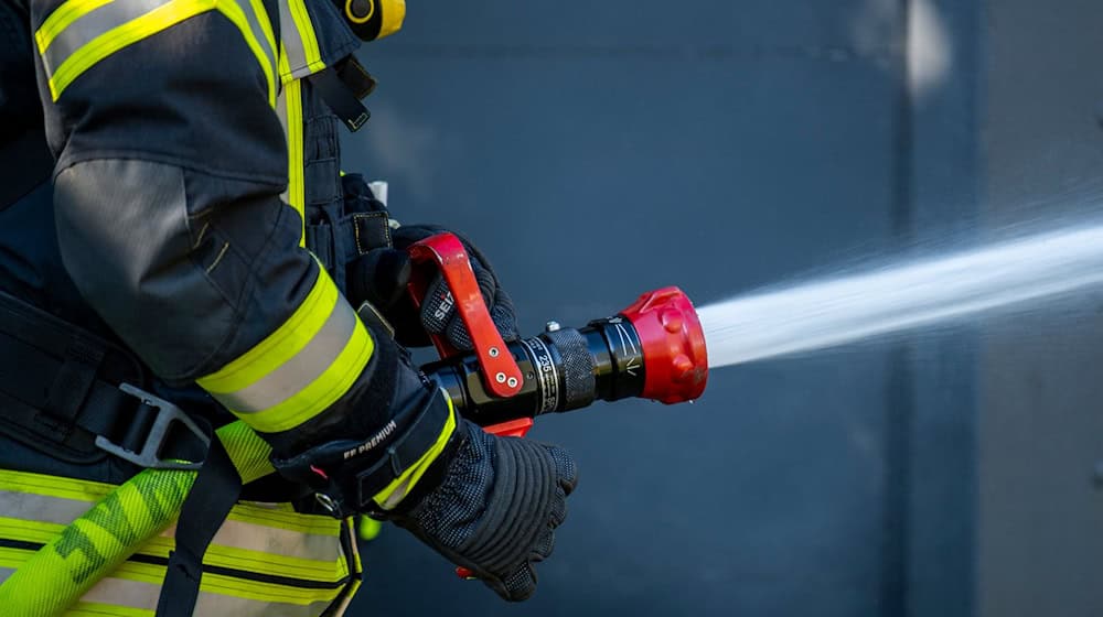 Ein Mitglied der Feuerwehr spritzt aus einem Schlauch mit Wasser. / Foto: David Inderlied/dpa/Symbolbild