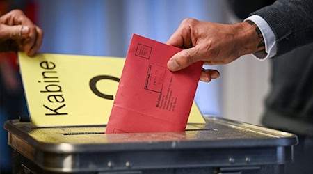 Ein Mann steckt seine Stimmzettel in einem Briefumschlag in die Wahlurne. / Foto: Jens Kalaene/dpa/Symbolbild