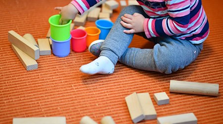 Ein Mädchen spielt in einer Kita mit bunten Bechern und Bauklötzen. / Foto: Uwe Anspach/dpa/Symbolbild