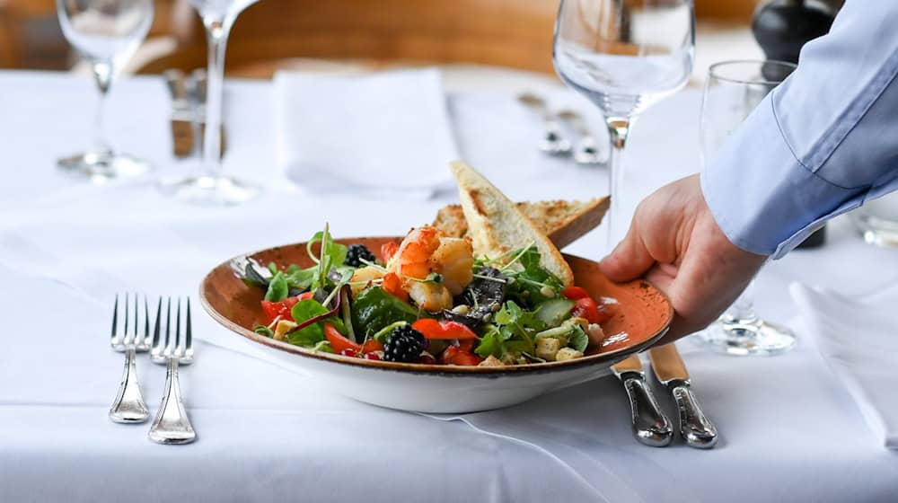 Ein Kellner serviert einen Salatteller in einem Restaurant. / Foto: Jens Kalaene/dpa/Symbolbild