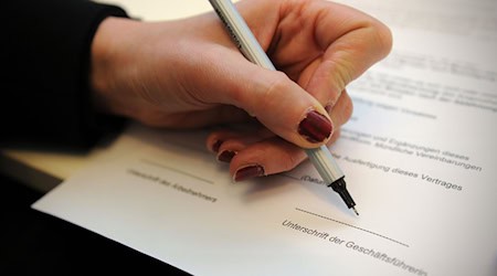 Eine Frau unterschreibt einen Arbeitsvertrag. / Foto: Jan-Philipp Strobel/dpa/Illustration