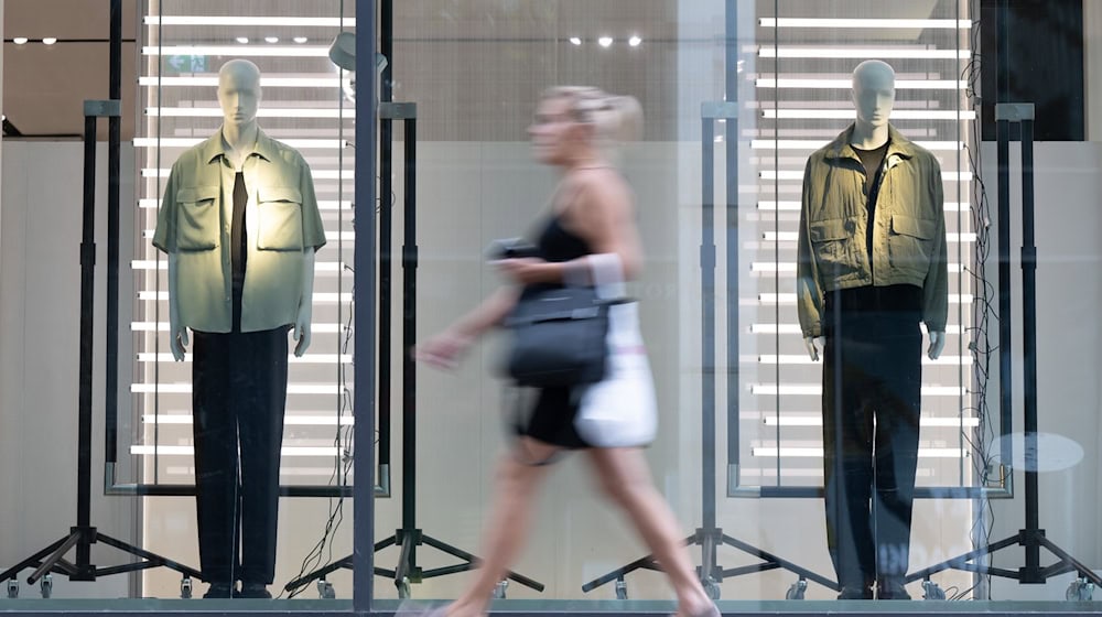 Eine Passantin gehen in einer Fußgängerzone an einem Schaufenster eines Modegeschäfts vorbei. / Foto: Sebastian Kahnert/dpa