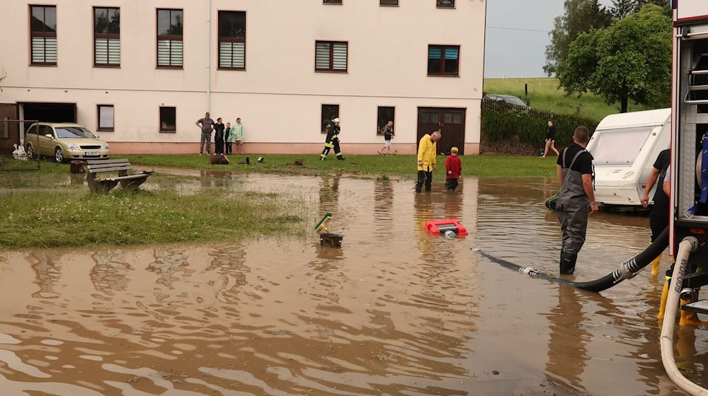 Nach einem Starkregen pumpen Einsatzkräfte der Feuerwehr auf einen Dorfplatz das Wasser ab. / Foto: Bodo Schackow/dpa