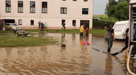 Nach einem Starkregen pumpen Einsatzkräfte der Feuerwehr auf einen Dorfplatz das Wasser ab. / Foto: Bodo Schackow/dpa