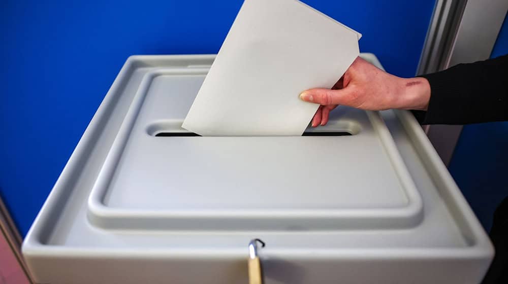 Eine Frau wirft einen Stimmzettel in eine Wahlurne. / Foto: Jan Woitas/dpa