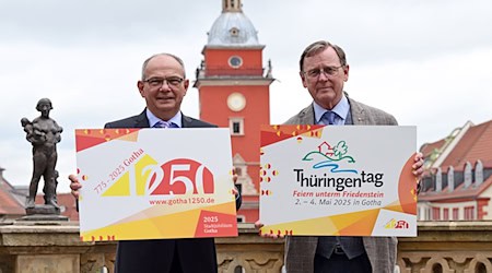 Gotha bereitet sich auf den Thüringentag 2025 vor. Ministerpräsident Bodo Ramelow (r.) und OB Knut Kreuch (SPD) mit den Logos von Landesfest und Stadtjubiläum vor dem Historischen Rathaus. / Foto: Martin Schutt/dpa