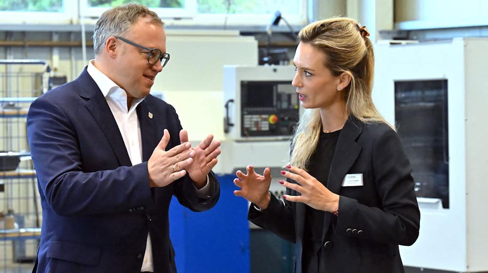 Mario Voigt (l, CDU), Ministerpräsident von Thüringen, spricht mit Karlotta Gründobler, Geschäftsführerin der Eliog Industrieofenbau GmbH. Voigt sieht überbordende Bürokratie als zunehmende Belastung für Thüringer Unternehmen.  / Foto: Martin Schutt/dpa