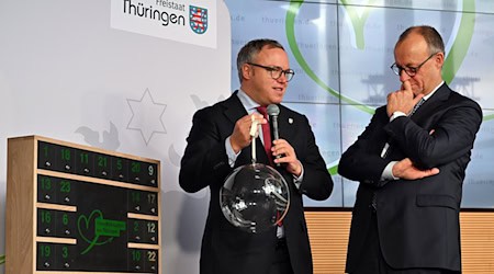 Thüringens Ministerpräsident Mario Voigt übergab Bundeskanzler Friedrich Merz (beide CDU) eine gläserne Weihnachtskugel. Das Weihnachtsfest verbringt der 48-Jährige im Kreise seiner Familie. (Archivbild) / Foto: Martin Schutt/dpa