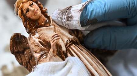 Einer Figur aus Papiermaché wird in der Marolin Manufaktur Steinach von Hand die Patina mit weichen Lappen von der Oberfläche gewischt. Das Unternehmen fertigt seit 125 Jahren auf diese Weise Figuren in Handarbeit.  / Foto: Martin Schutt/dpa