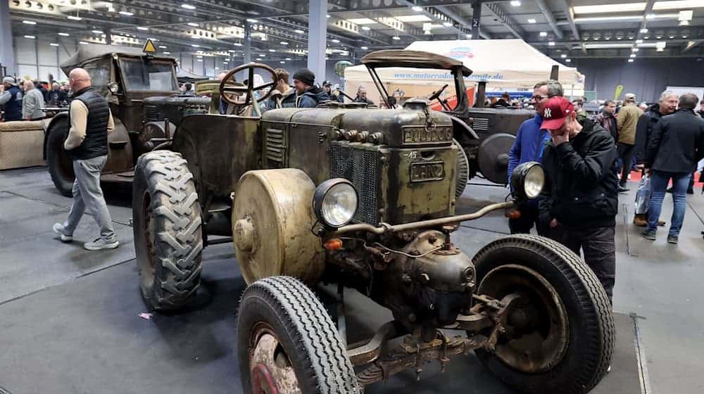 Hochglanzautos stehen auf der Messe neben alten Traktoren.  / Foto: Bodo Schackow/dpa