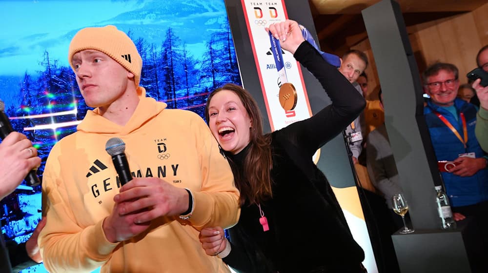 Rodler Max Langenhan steht mit seiner Freundin Susi auf der Bühne und singt das Thüringenlied mit seinen Fans. / Foto: Frank May/ picture alliance/Team D/dpa