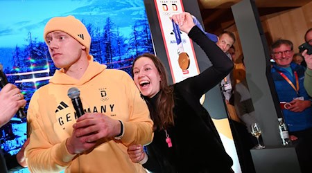 Rodler Max Langenhan steht mit seiner Freundin Susi auf der Bühne und singt das Thüringenlied mit seinen Fans. / Foto: Frank May/ picture alliance/Team D/dpa