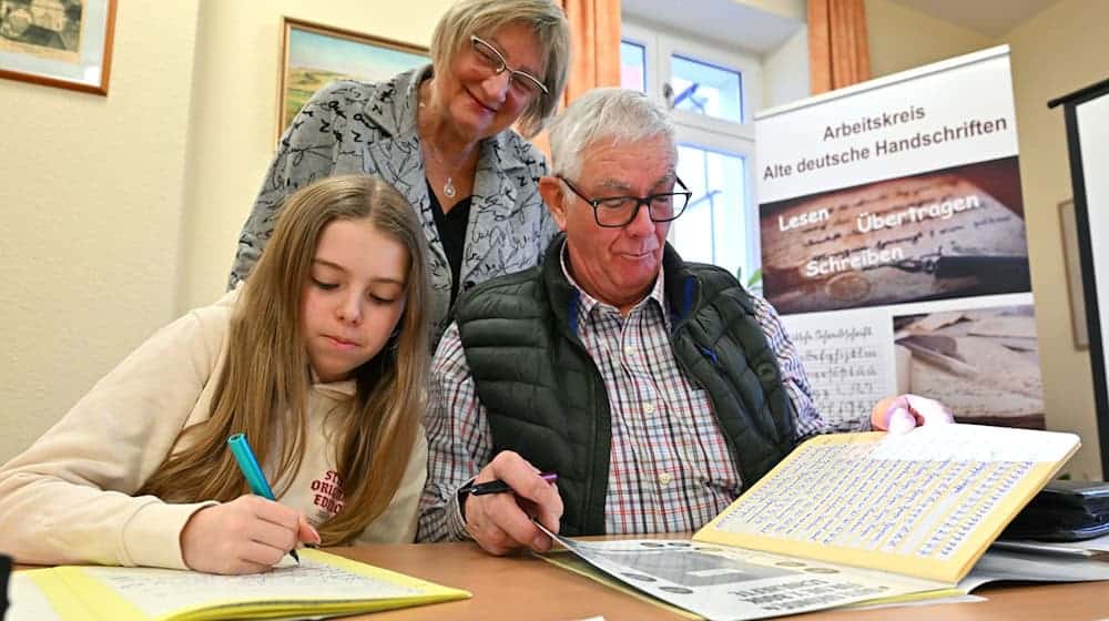 Im Sütterlin-Kurs lernen Enkelin Tamara und Großvater Heinrich Heckeroth zusammen, die alte Schrift auf das Papier zu bringen. Dozentin Birgit Tröße kontrolliert das Geschriebene.   / Foto: Martin Schutt/dpa