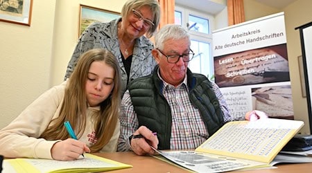 Im Sütterlin-Kurs lernen Enkelin Tamara und Großvater Heinrich Heckeroth zusammen, die alte Schrift auf das Papier zu bringen. Dozentin Birgit Tröße kontrolliert das Geschriebene.   / Foto: Martin Schutt/dpa