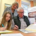 Im Sütterlin-Kurs lernen Enkelin Tamara und Großvater Heinrich Heckeroth zusammen, die alte Schrift auf das Papier zu bringen. Dozentin Birgit Tröße kontrolliert das Geschriebene.   / Foto: Martin Schutt/dpa