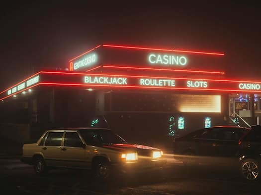 Casino-Gebäude bei Nacht mit Neonreklame für Blackjack, Roulette und Slots