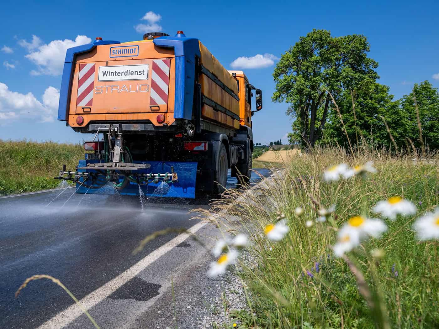 Das Fahrzeug des Winterdienstes ist im Einsatz, um den Asphalt zu kühlen. / Foto: Jacob Schröter/dpa