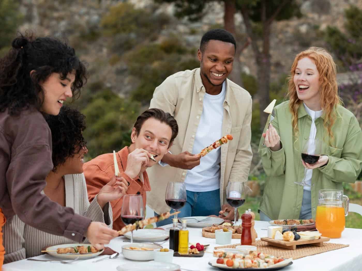 Freunde genießen gemeinsam gegrillte Spieße mit Gemüse und Fleisch an einem sommerlichen Abend