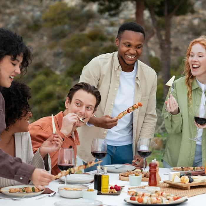 Freunde genießen gemeinsam gegrillte Spieße mit Gemüse und Fleisch an einem sommerlichen Abend
