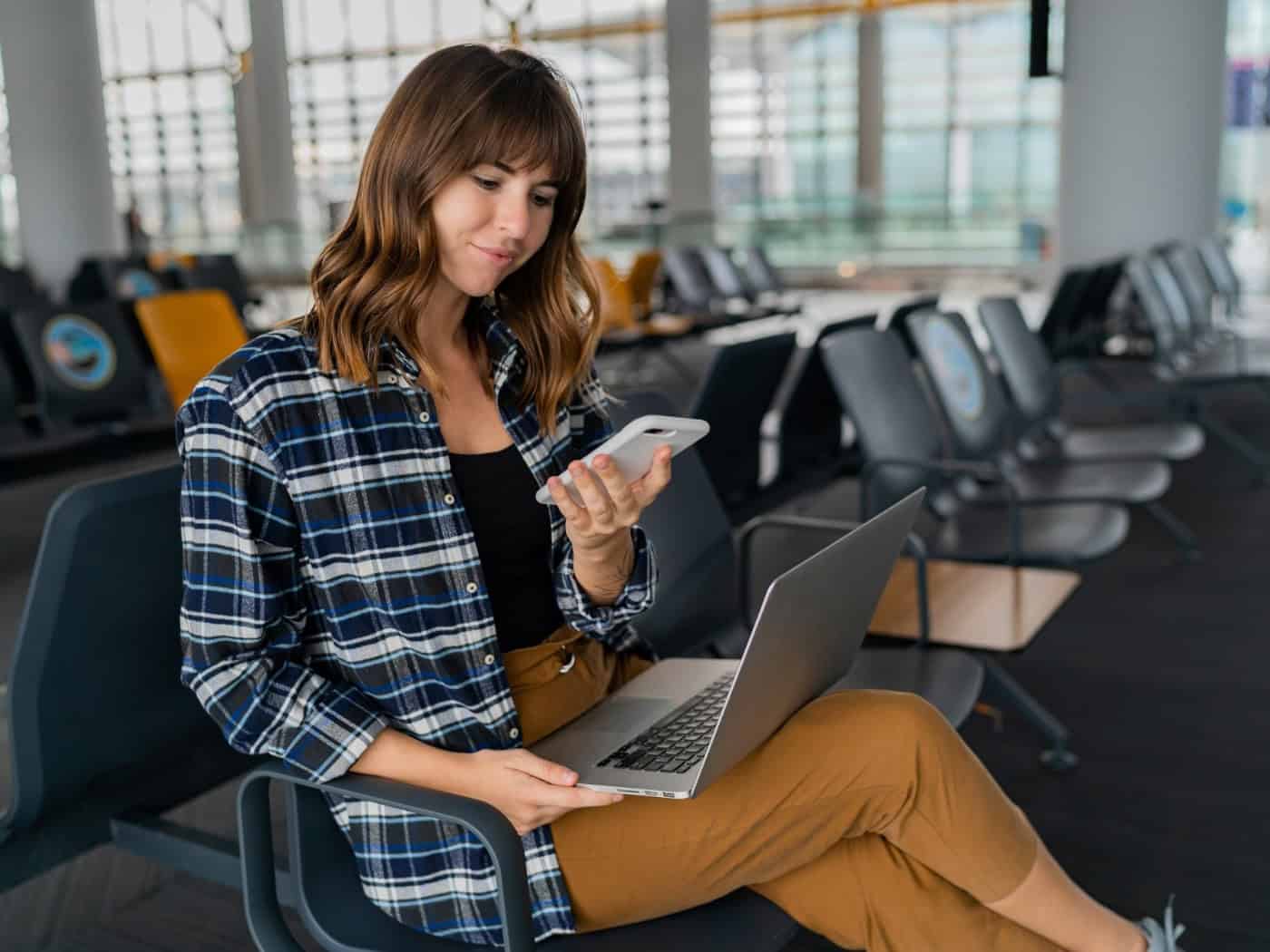Frau am Flughafen mit Laptop und Smartphone