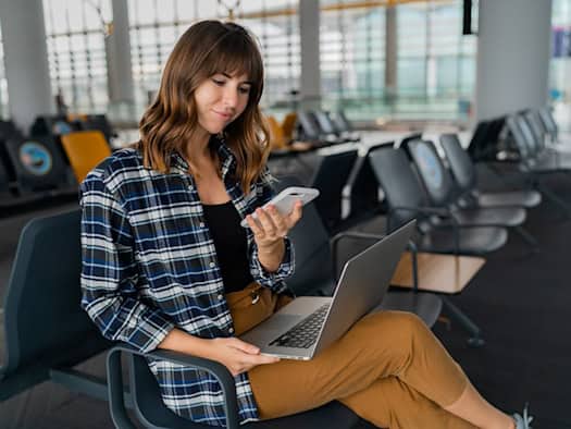 Frau am Flughafen mit Laptop und Smartphone