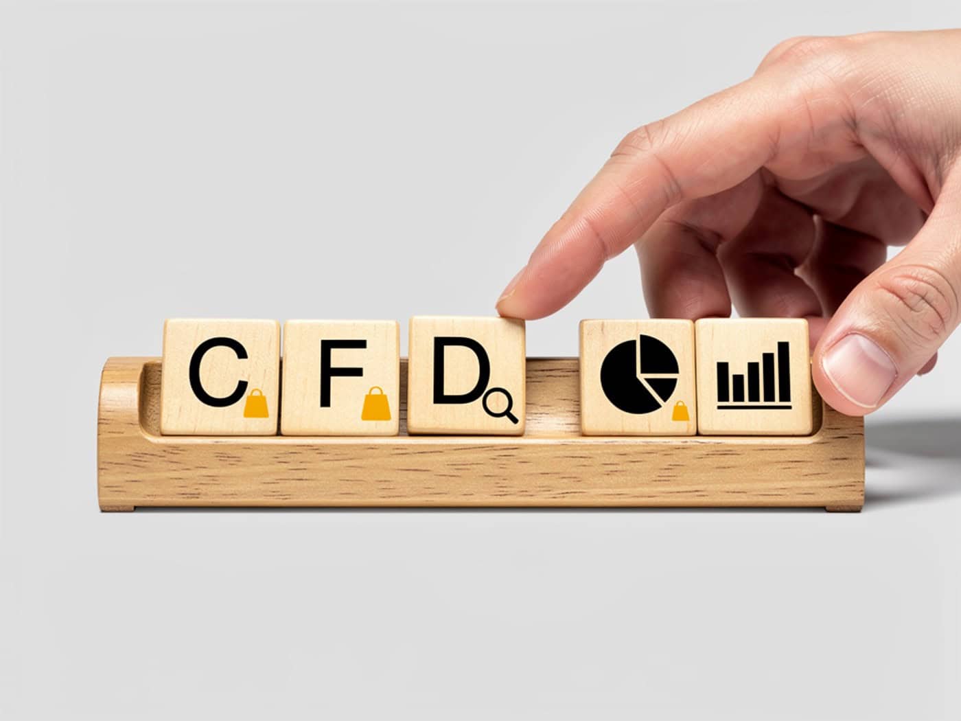 Hand legt Holzblock mit dem Buchstaben "D" zu den Buchstaben "C", "F" und Symbolen für Handel und Analyse, die CFD (Contract for Difference) darstellen.
