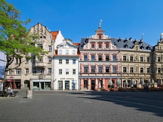 Erfurts historische Altstadtfassaden in Pastellfarben mit Cafés, Grün und blauem Himmel über gepflastertem Platz