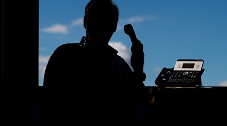 Ein Mann hält ein Telefon. / Foto: Julian Stratenschulte/dpa/Archivbild